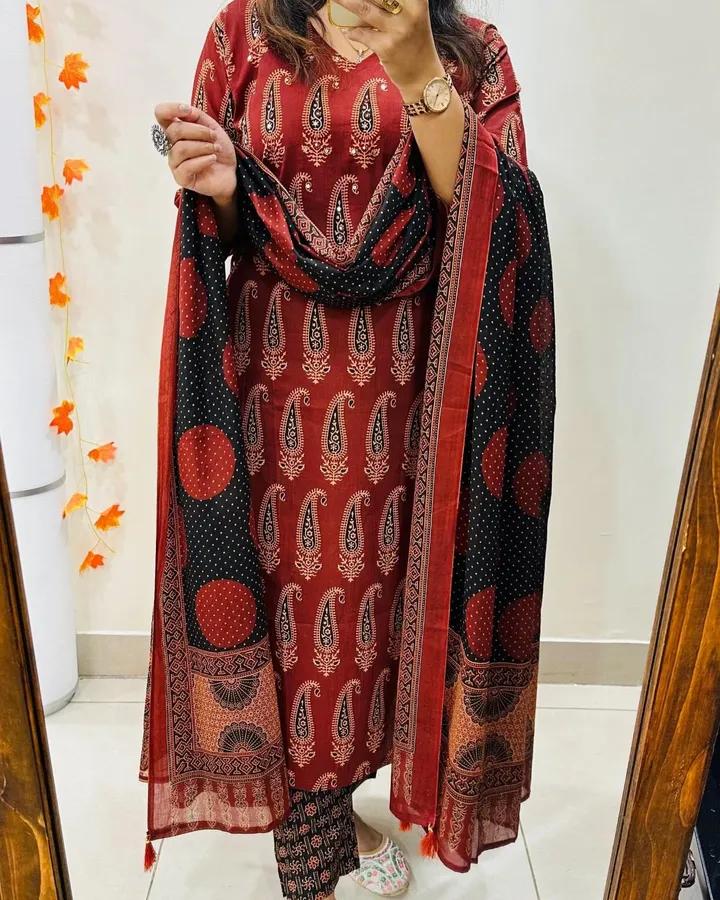 Woman wearing a red and black patterned outfit with a matching dupatta in a bathroom setting.