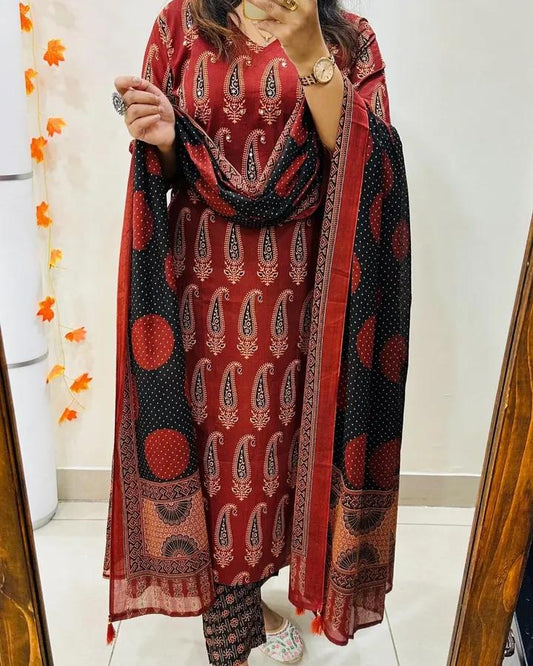 Woman wearing a red and black patterned outfit with a matching dupatta in a bathroom setting.