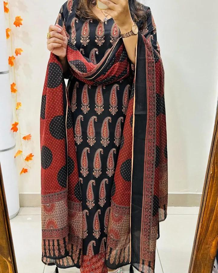 Person wearing a patterned dress with a matching shawl in a room.