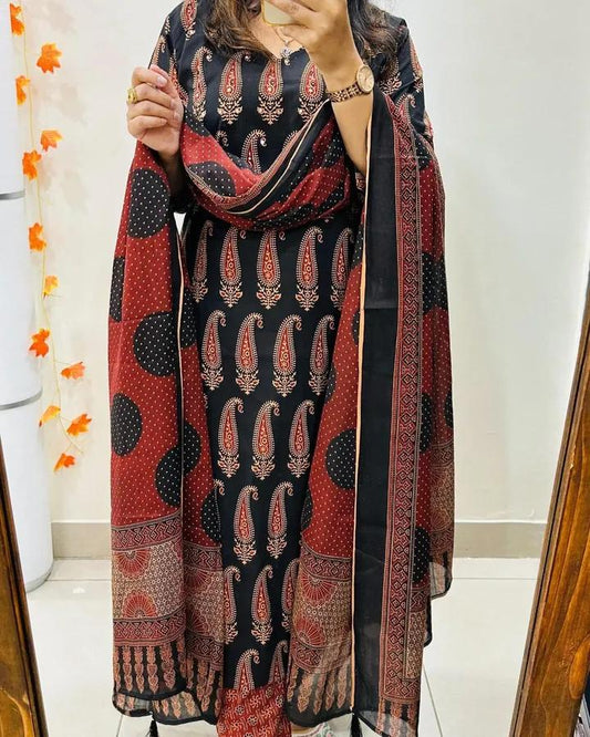 Person wearing a patterned dress with a matching shawl in a room.