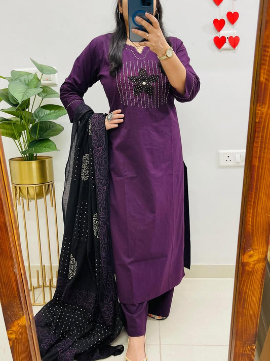 Person wearing a purple outfit with black embellishments in a room.