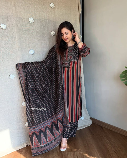 Woman wearing a traditional outfit with a patterned dupatta in a room.
