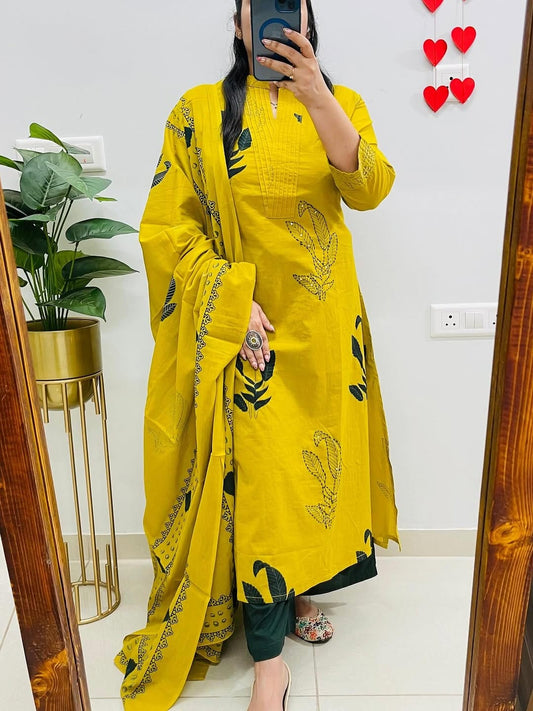 Person wearing a yellow traditional outfit with black patterns in a room.