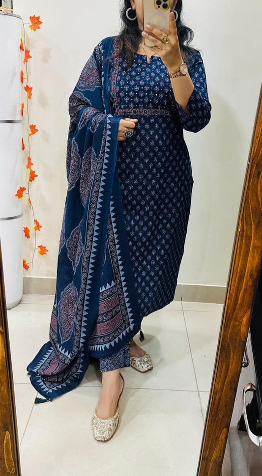 Person wearing a blue patterned dress standing in front of a mirror.