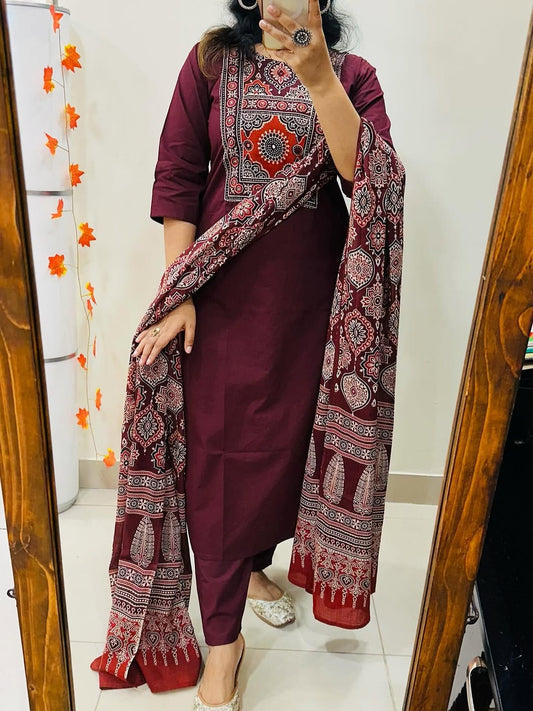 Person wearing a maroon traditional outfit with a patterned scarf in front of a mirror.