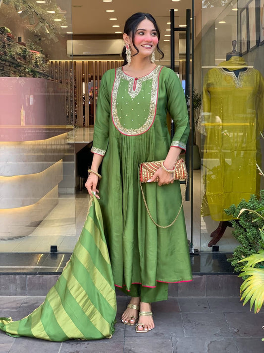 Woman in a green traditional outfit holding a matching dupatta in a store setting
