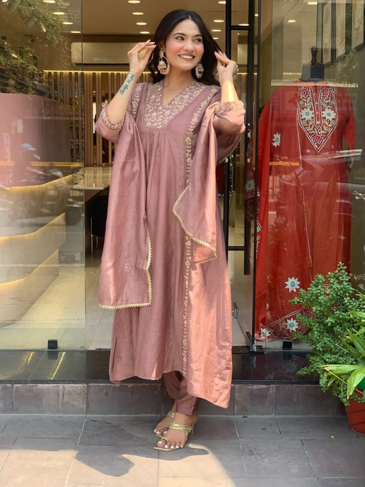 Woman in a pink traditional outfit standing in front of a store entrance.