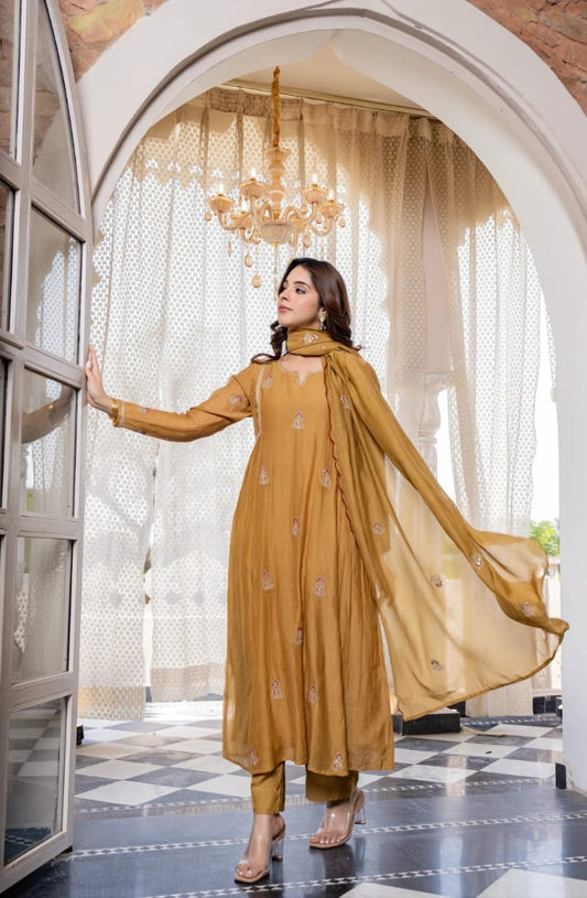Woman in a mustard yellow traditional outfit standing in an elegant interior setting with a chandelier.